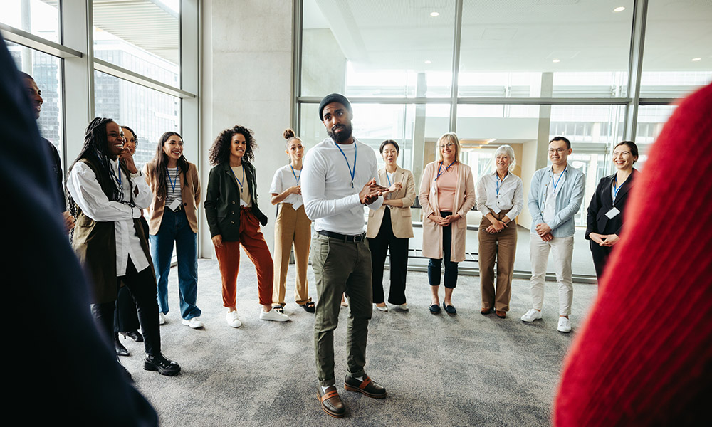 Instructor guides team building exercise at conference with a diverse group of people. Concept of teamwork, communication, and learning in a professional setting.